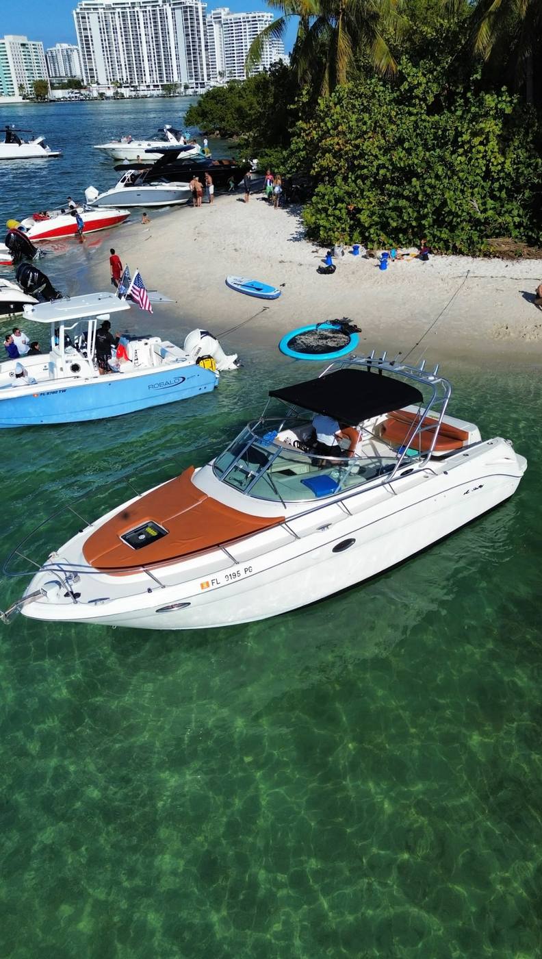 Anchored off a sandbar beach with other boats along the shore