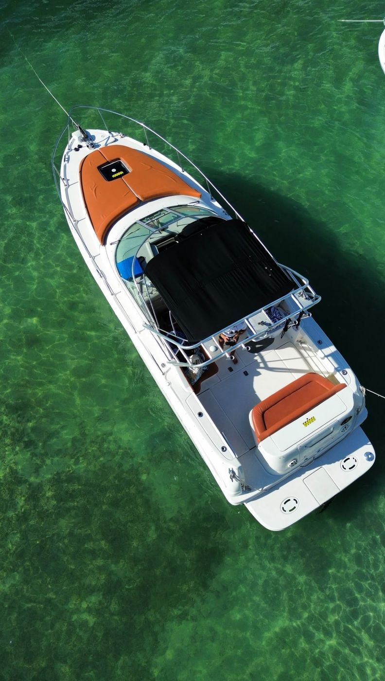 The Amberjack 32 at anchor in turquoise water, bimini up