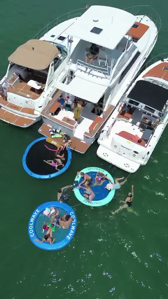 Aerial view of three LuxSea boats rafted together at the Miami sandbar, floating pools tied alongside in green water