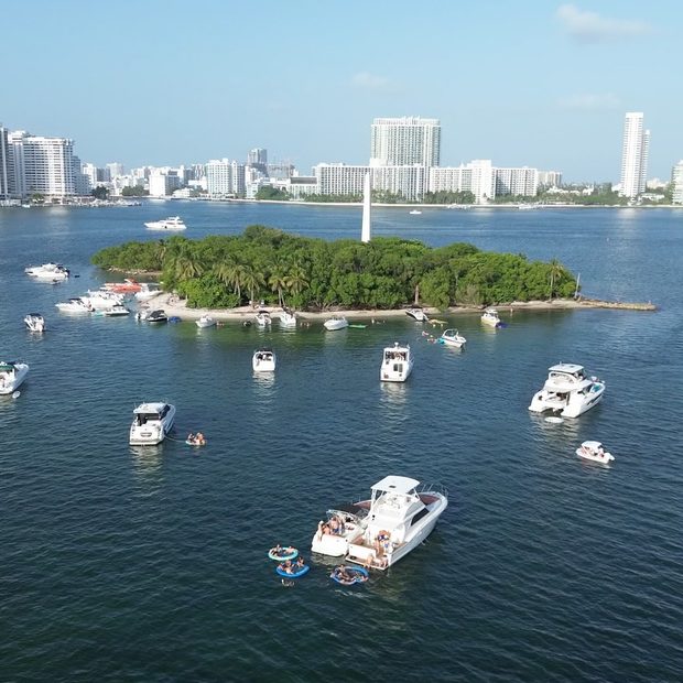 Aerial view of boats anchored all around a mangrove island off Miami Beach, the city towers behind