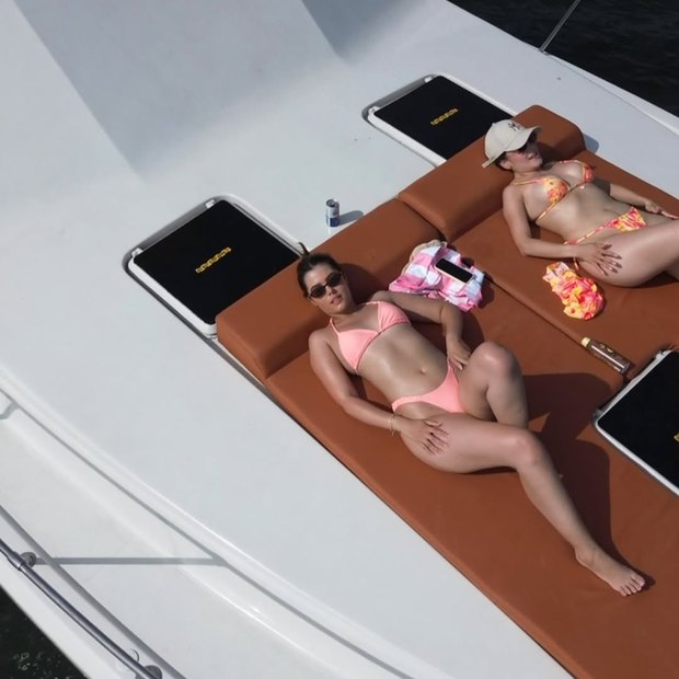 Two guests sunbathing on the bow cushions in the middle of the afternoon